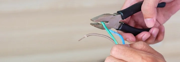 Person schneidet Kabel mit Zange